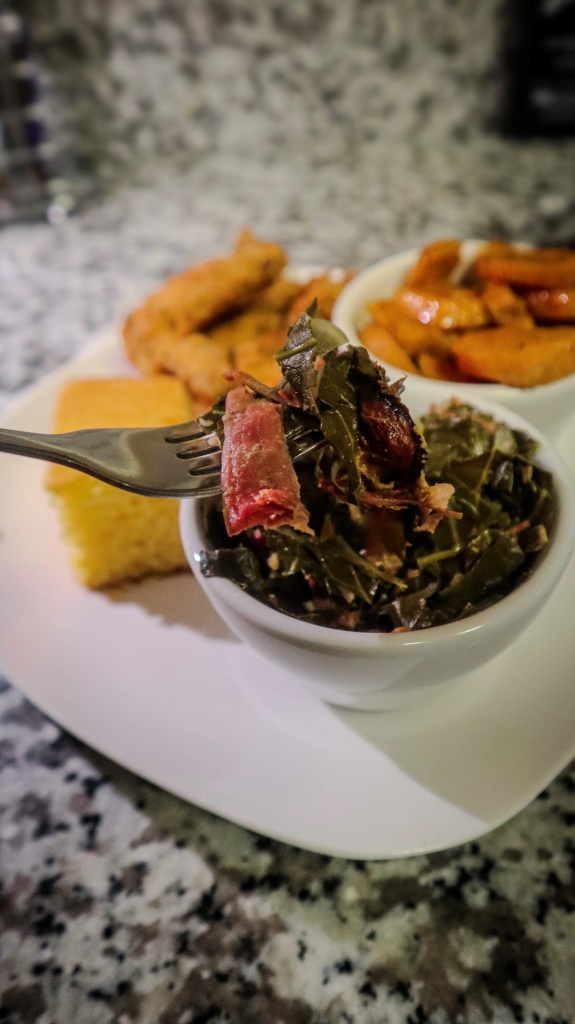 a fork garnished with collard greens from a small bowl.